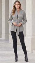 Full front view of model wearing grey textured belted utility jacket with black leggings and boots