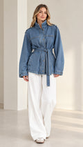 Front full-length view of model wearing denim blue belted utility jacket with white wide-leg pants
