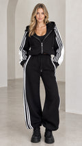 Front view of model wearing black cropped zip hoodie and wide-leg striped tracksuit set