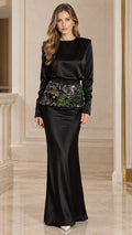 Front full-length view of woman wearing black long sleeve satin evening maxi gown with floral embroidered waist