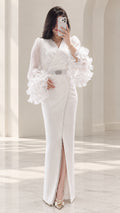 Front full view of white long sleeve maxi evening gown with ruffle cuffs and crystal belt