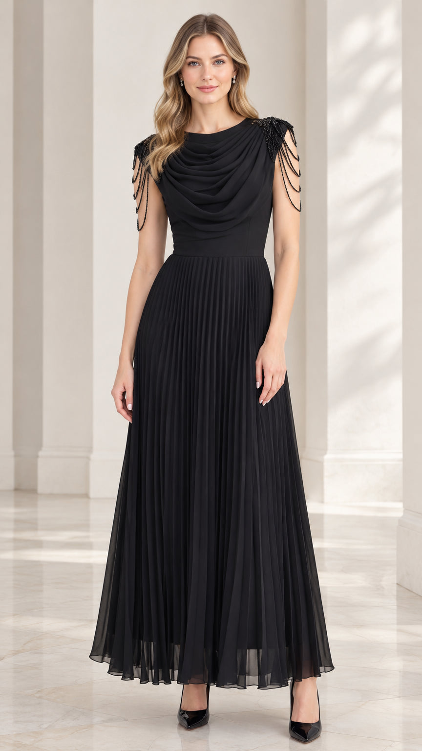 Front view of model wearing black cowl neck pleated maxi evening dress with beaded shoulder fringe