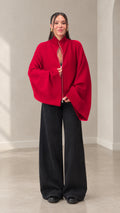 Front full view of woman wearing red zip-front batwing sleeve cardigan with black wide leg pants