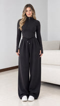 Front view of model wearing black half zip top and wide leg sweatpants lounge set