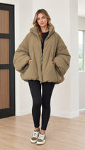 Front view of woman wearing olive green oversized bubble puffer jacket with leggings and sneakers