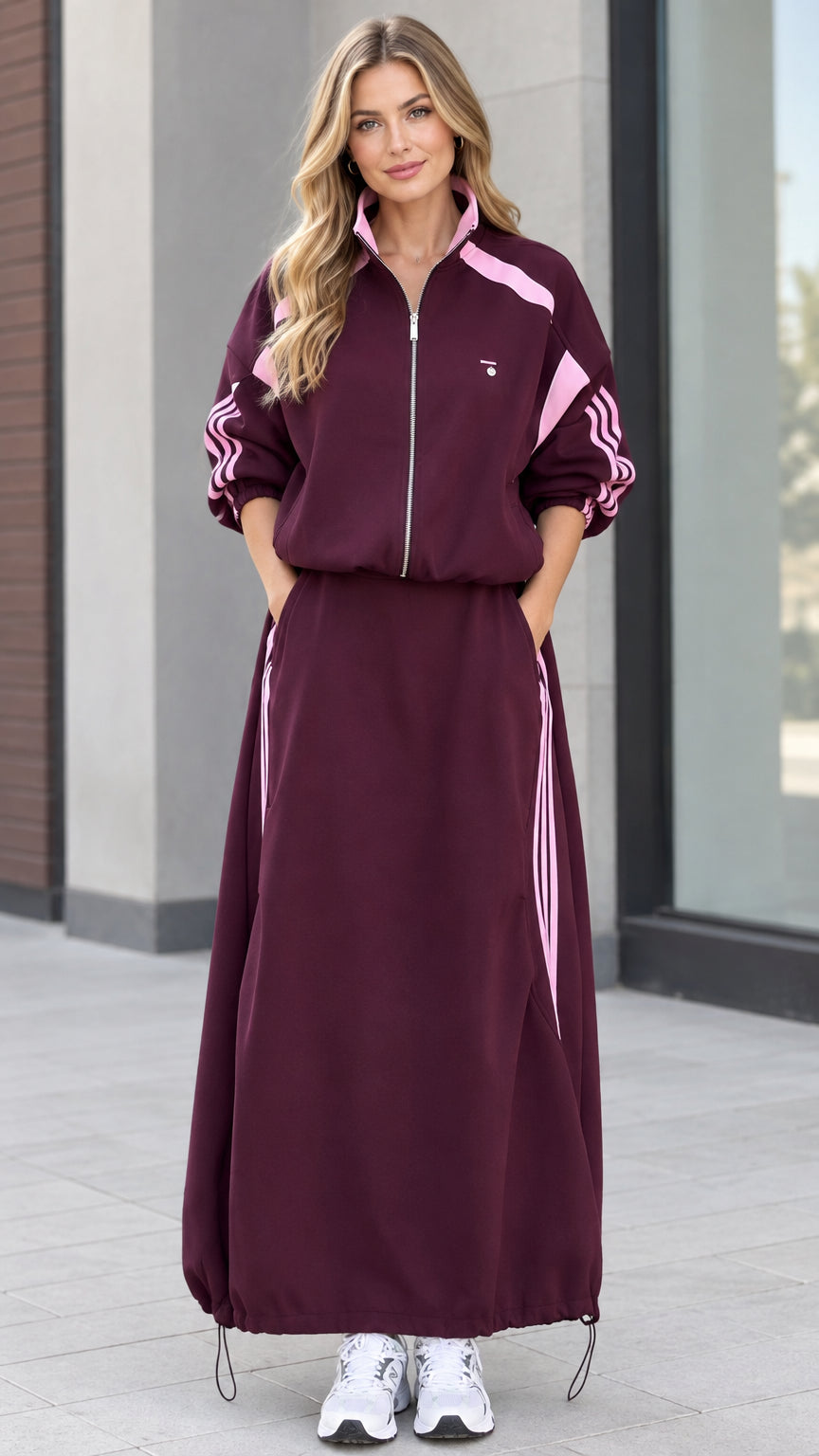 Front full view of woman wearing burgundy sporty track jacket and maxi skirt set with pink stripes