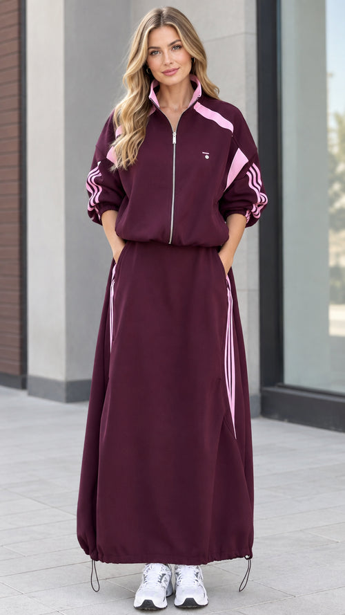 Front full view of woman wearing burgundy sporty track jacket and maxi skirt set with pink stripes