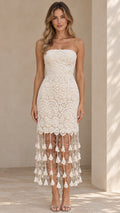 Front view of model wearing cream strapless lace midi dress with beaded tassel hem