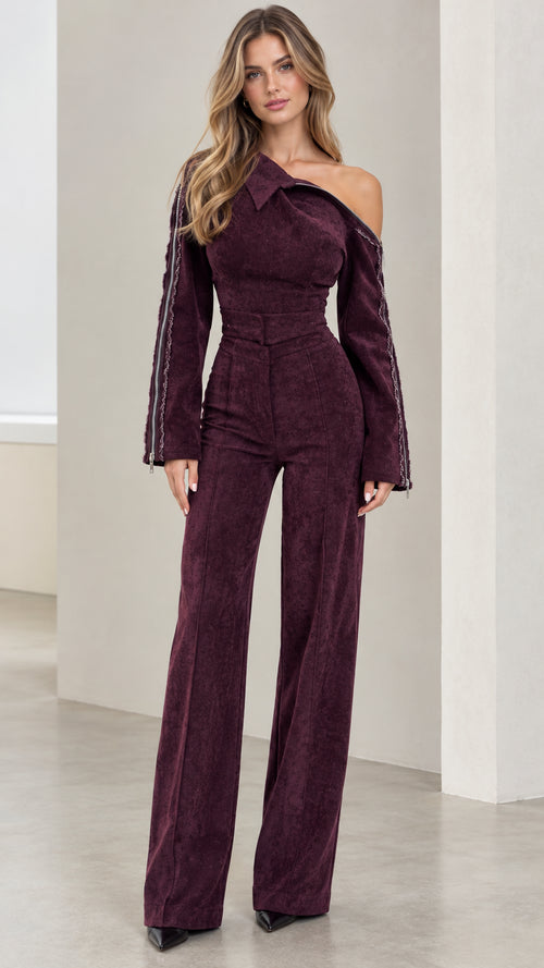 Front full-length view of model wearing Burgundy asymmetrical off-shoulder wide-leg jumpsuit