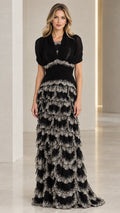 Front full view of black sequined tiered evening gown with draped bodice