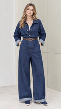 Front full-length view of woman wearing a denim blue wide-leg utility jumpsuit with belt