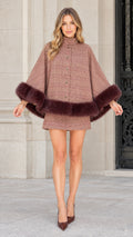 Front view of model wearing a dusty rose plaid cape coat with plush faux fur trim and matching skirt