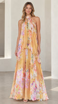 Front view of model wearing a yellow floral halter neck tiered maxi dress
