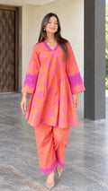 Front full view of woman wearing coral floral print flared tunic and pants set with lace trim