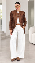 Front full-length view of model wearing brown faux suede fringe jacket with white trousers