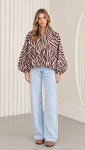 Front view of model wearing mocha brown zebra print balloon sleeve zip-up jacket with light-wash wide-leg jeans