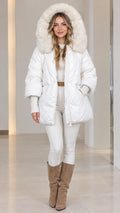 Front full view of woman wearing white faux fur hooded quilted puffer coat with white pants and boots