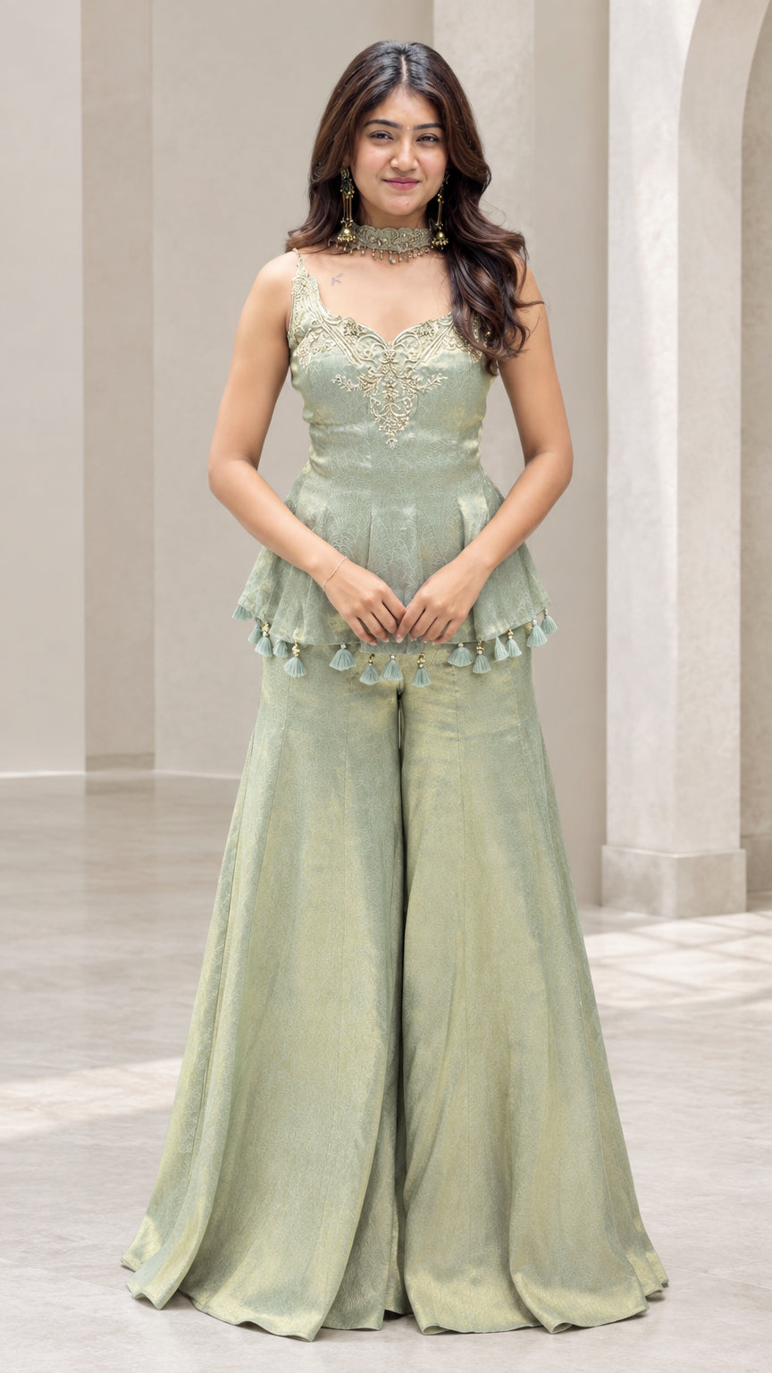 Front full view of woman wearing sage green embroidered peplum top and flared sharara pants set