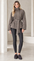 Front view of model wearing taupe high-neck belted faux suede jacket with black leggings