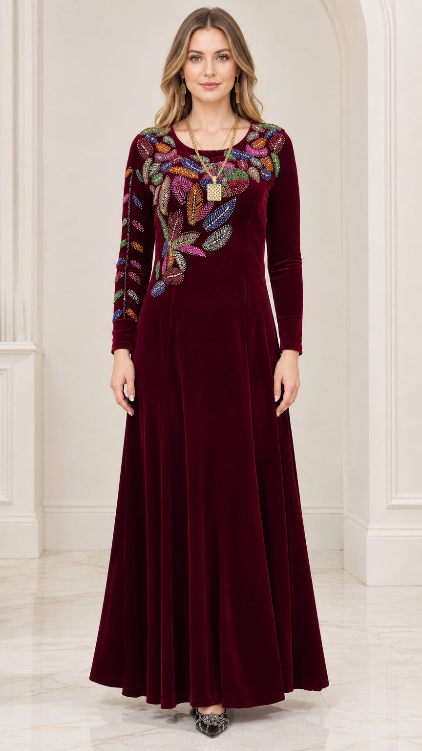 Front view of woman wearing burgundy velvet maxi dress with colorful embroidered leaf details
