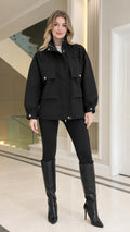 Front view of model wearing black embellished utility jacket with knee-high boots