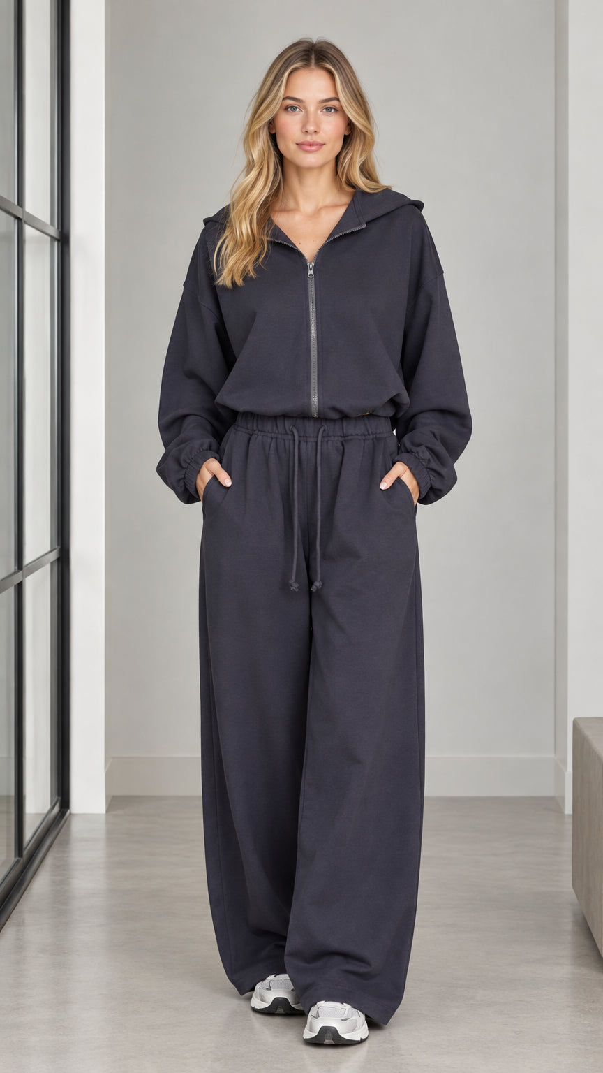 Front full-length view of woman wearing a charcoal zip-front hooded wide-leg jumpsuit