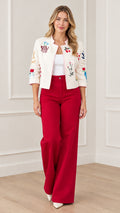 Front view of model wearing cream embroidered cropped jacket with red wide-leg trousers