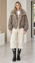Model wearing taupe faux fur collar bomber jacket front view with cream cargo pants