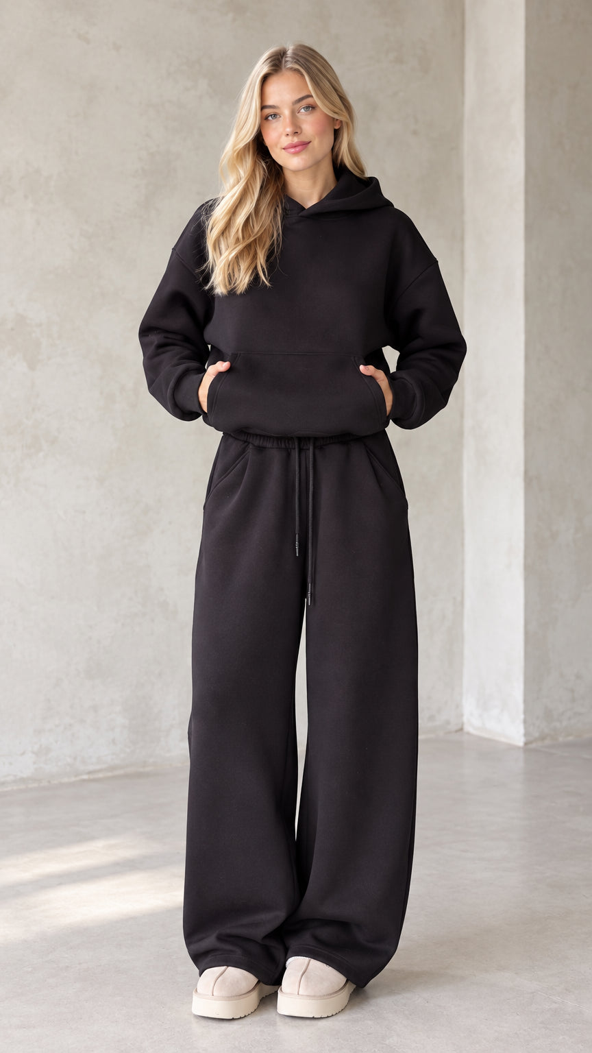 Front view of woman wearing black oversized hoodie and matching wide leg sweatpants