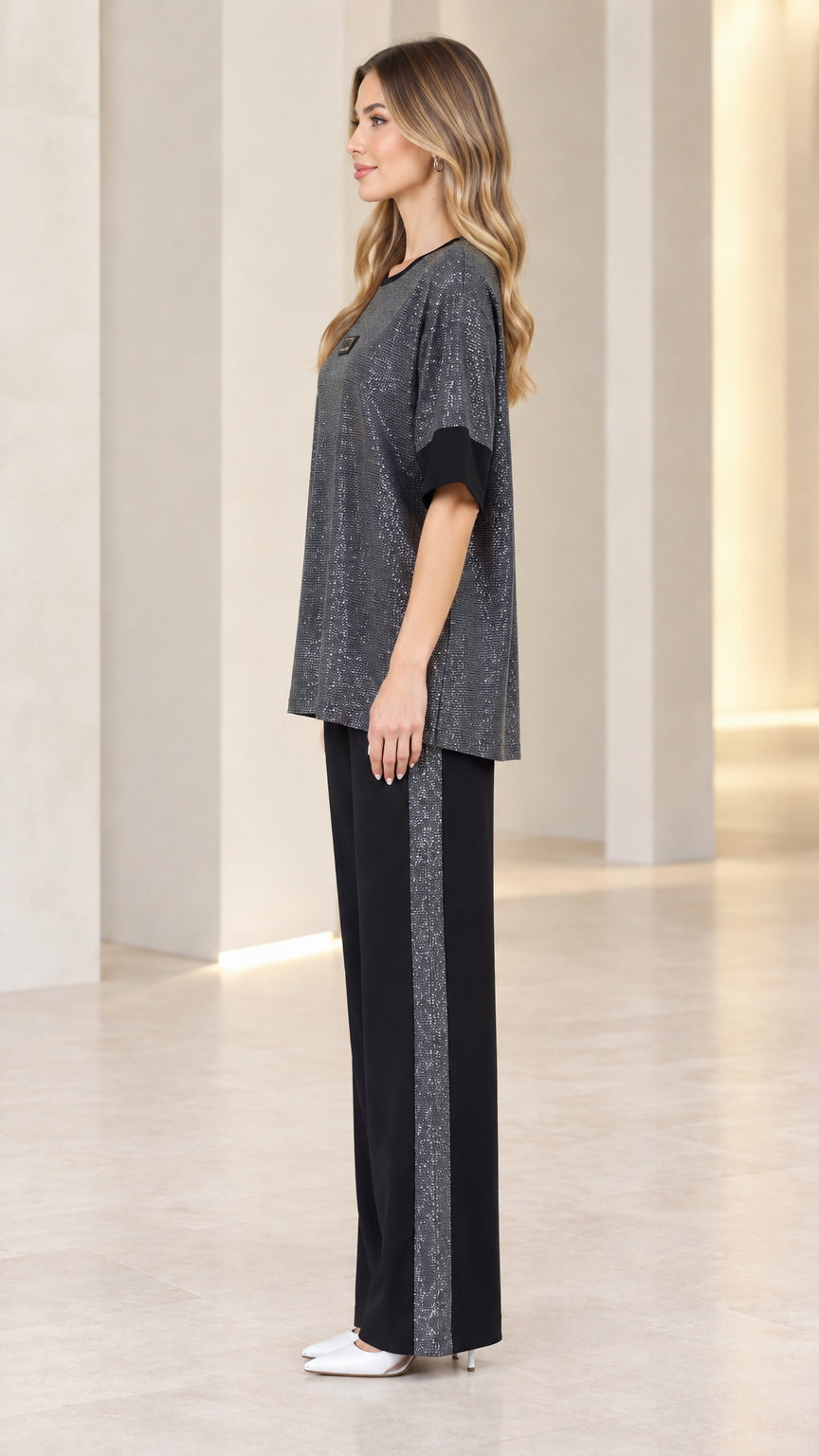 Side profile view of model wearing charcoal metallic knit two-piece outfit