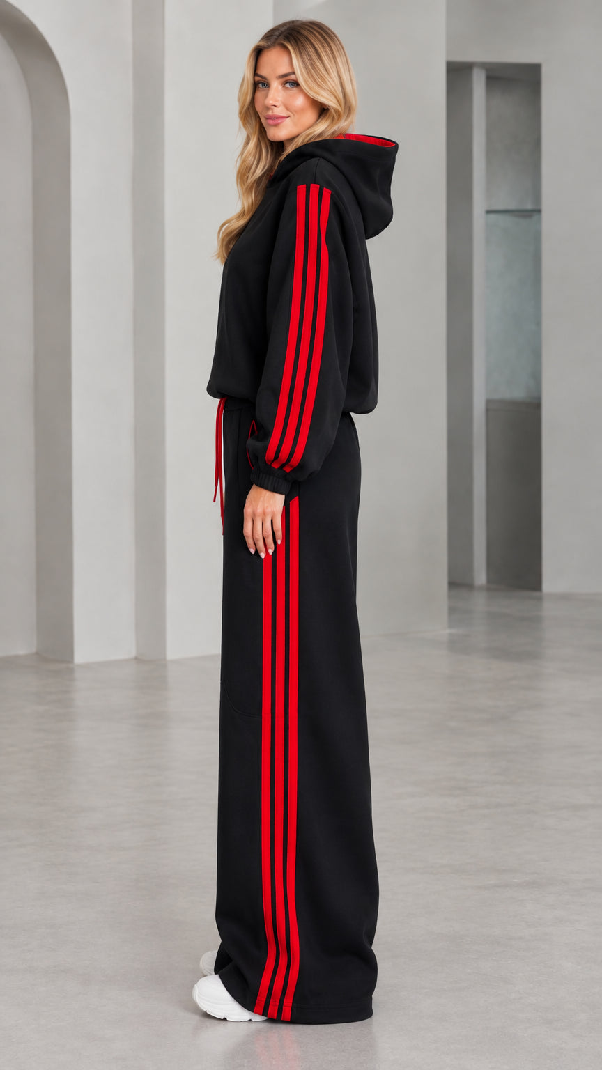 Side profile of woman in black two-piece wide leg tracksuit with red side stripes