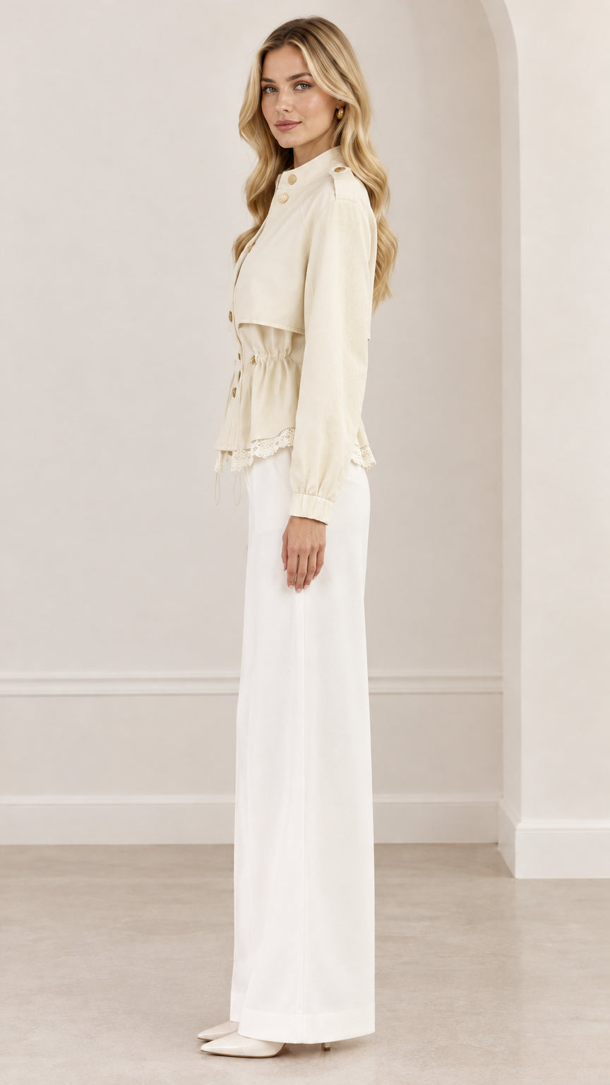 Side profile view of woman wearing cream drawstring peplum jacket with lace trim