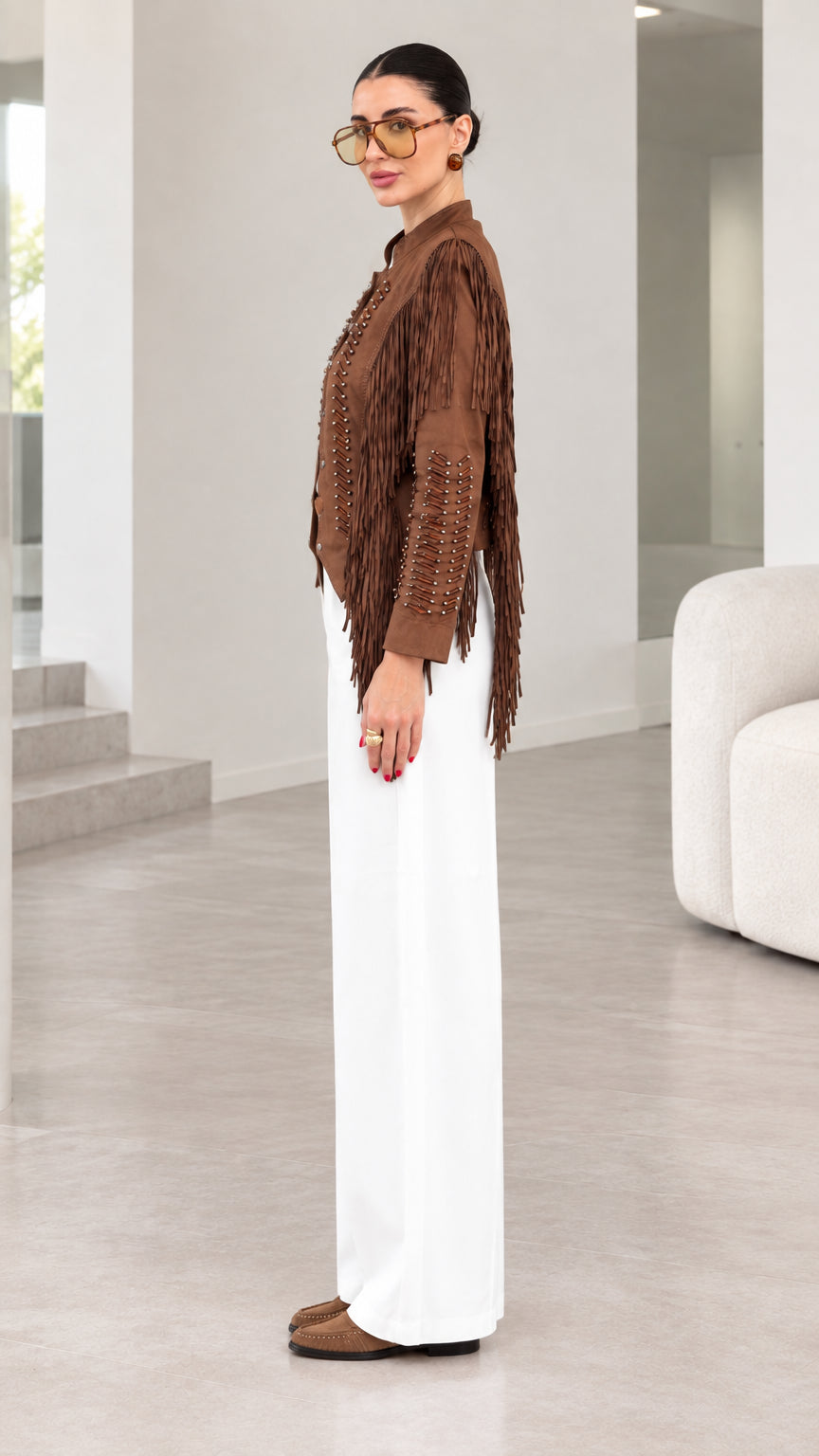 Side profile view of model showcasing sleeve fringe on brown suede jacket