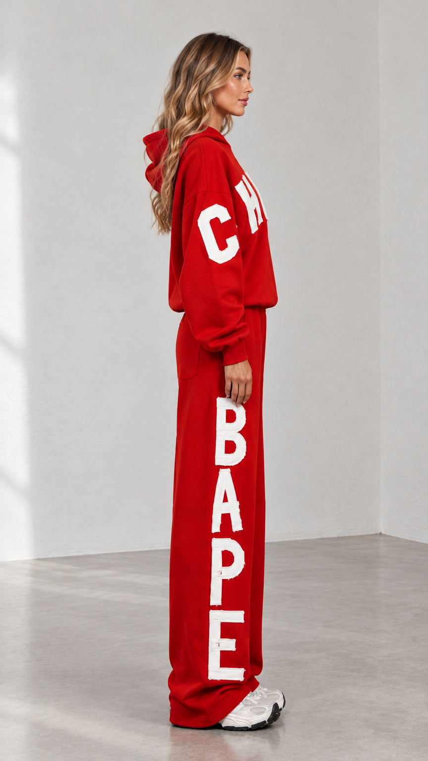 Side profile view of woman wearing red 2-piece tracksuit set showing vertical leg lettering