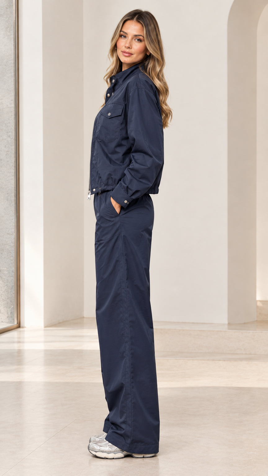Side profile view of woman wearing navy blue windbreaker two-piece set