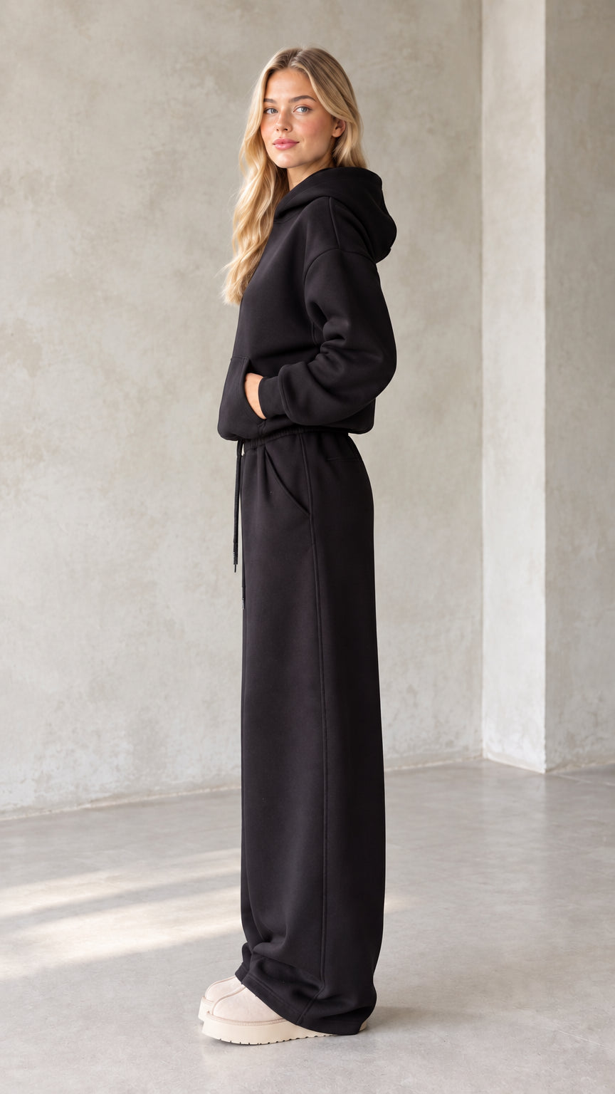 Side profile view of black fleece hoodie and wide leg sweatpants set