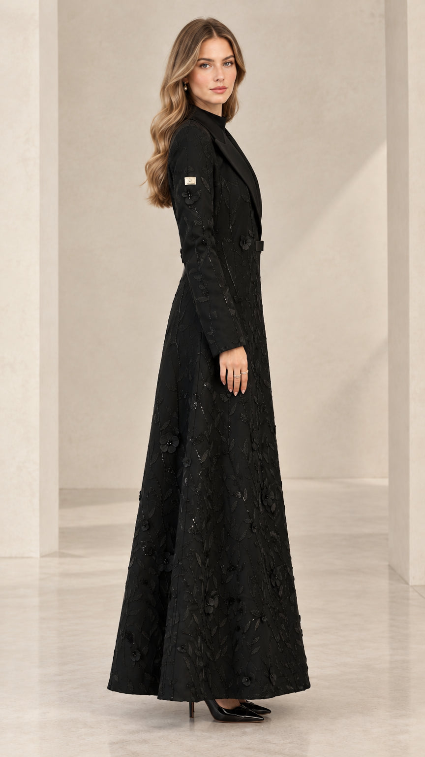 Side profile view of woman wearing black embroidered floor-length coat