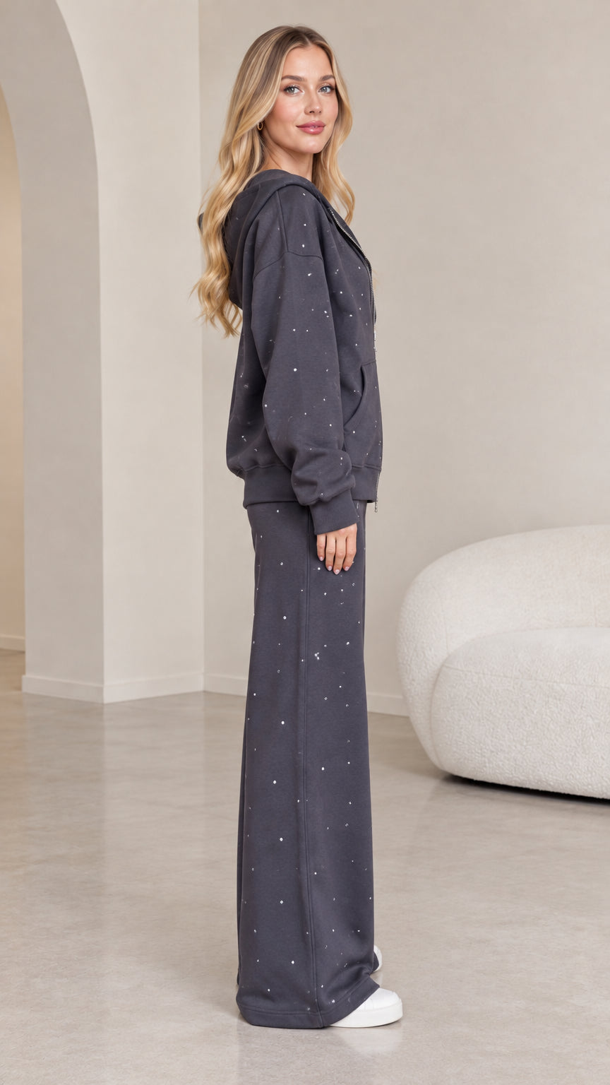 Side profile view of dark grey rhinestone two-piece tracksuit set on model