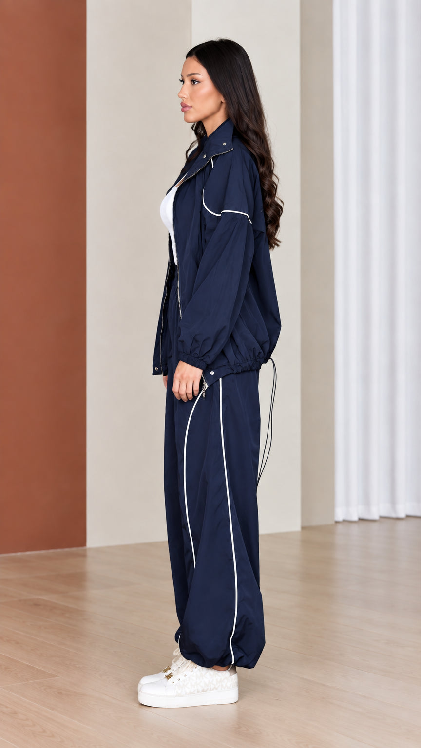 Side profile of woman wearing navy windbreaker jacket and matching parachute pants