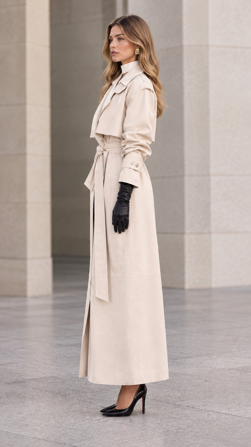 Side profile view of woman modeling longline cream trench coat with waist sash