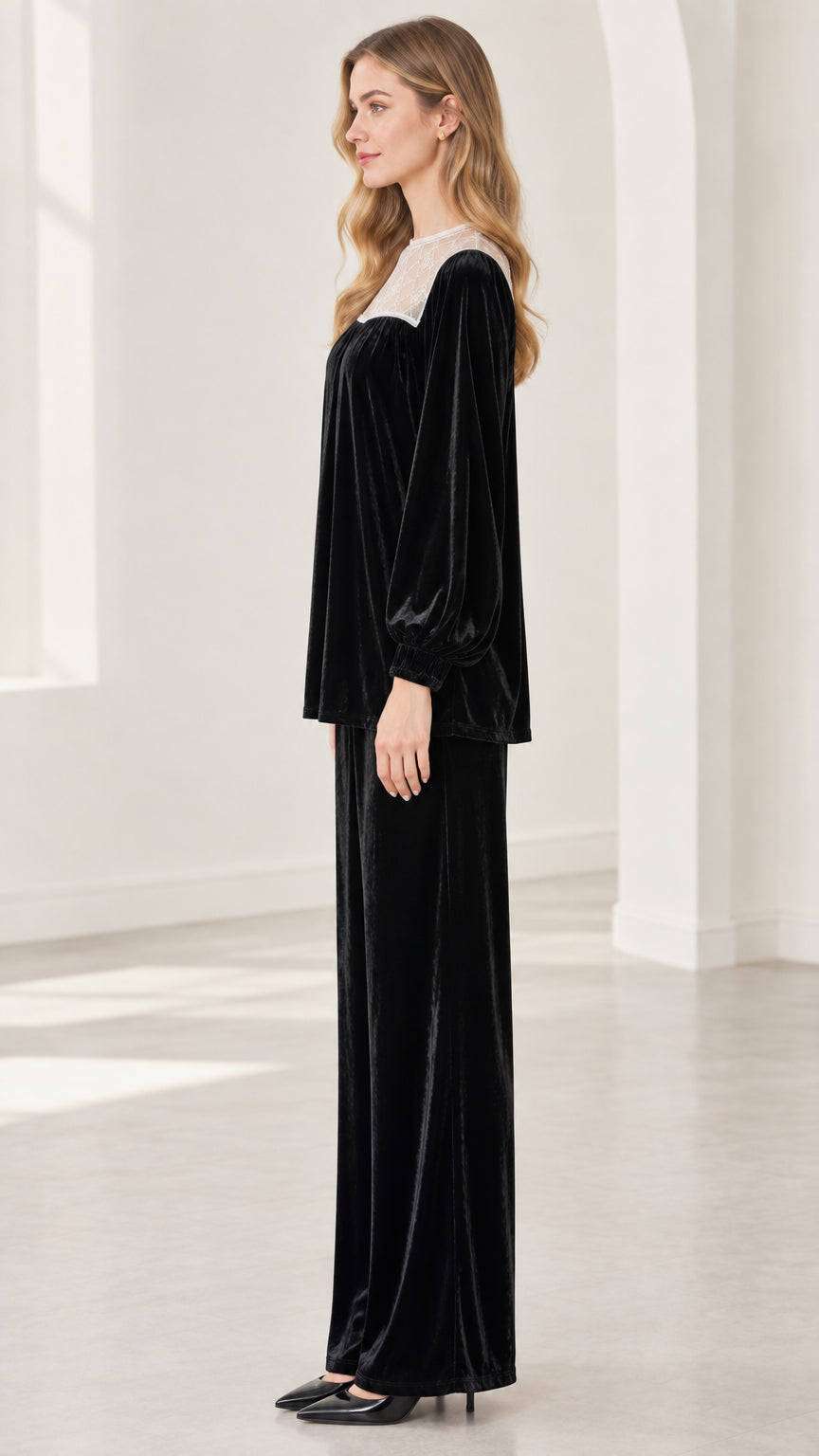 Side profile view of model in black velvet two-piece top and matching trousers
