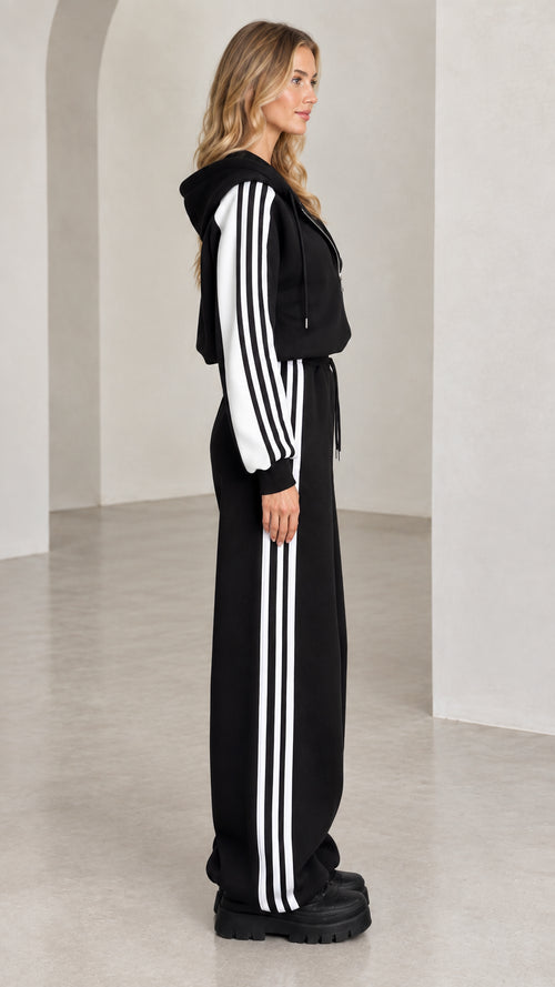Side profile of model wearing black two-piece striped track set