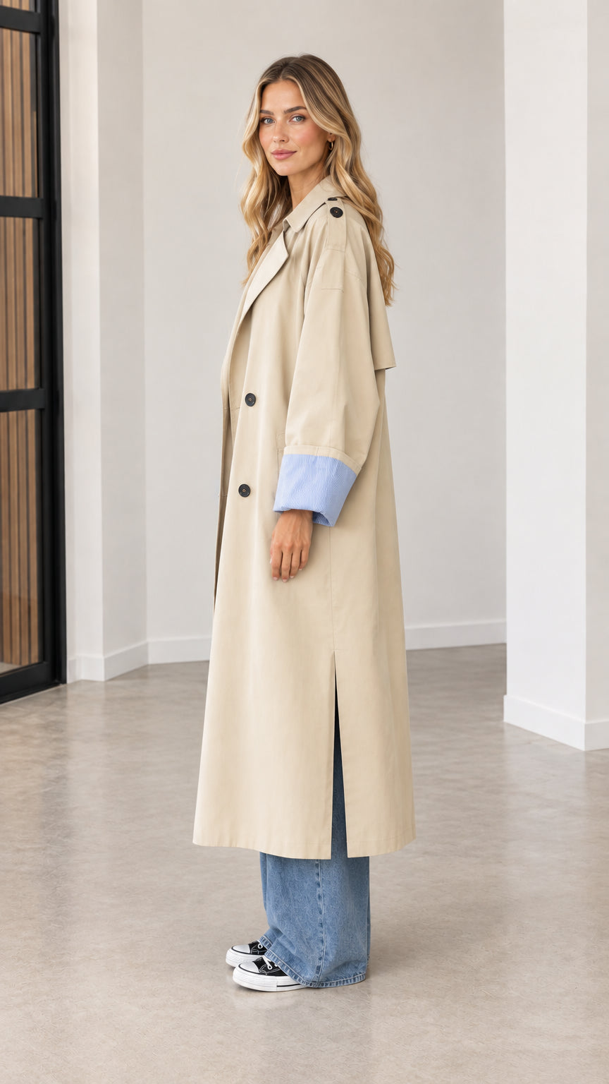 Side profile view of beige longline trench coat showing side split hem and relaxed fit