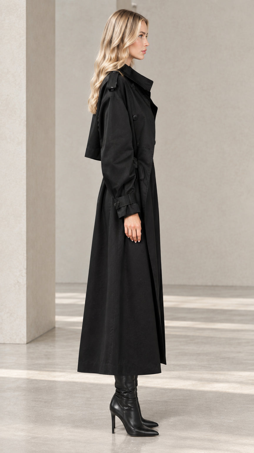 Side profile view of women's black maxi trench coat showing sleeve drape and length