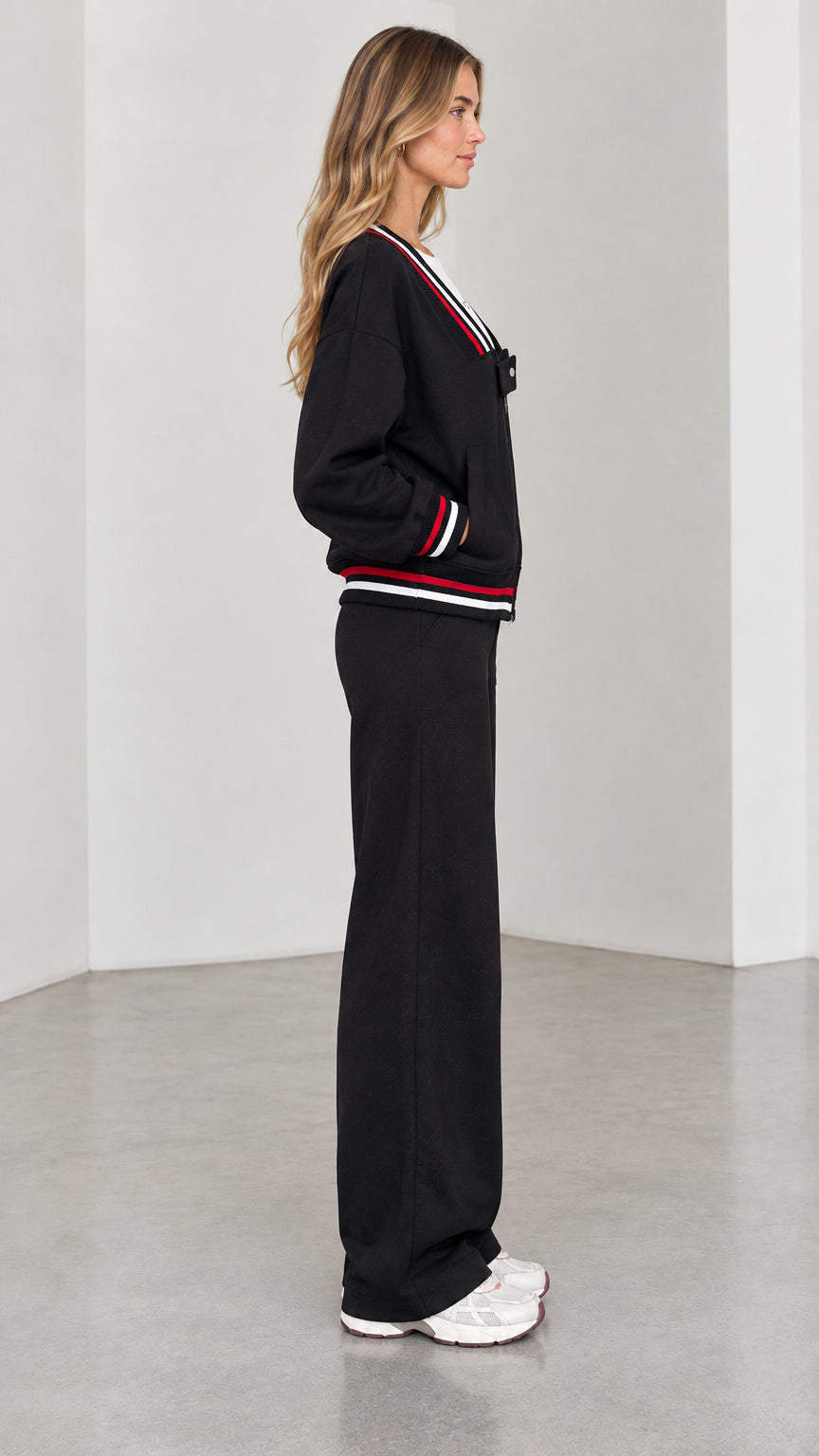 Side profile view of model in black two-piece wide leg tracksuit set