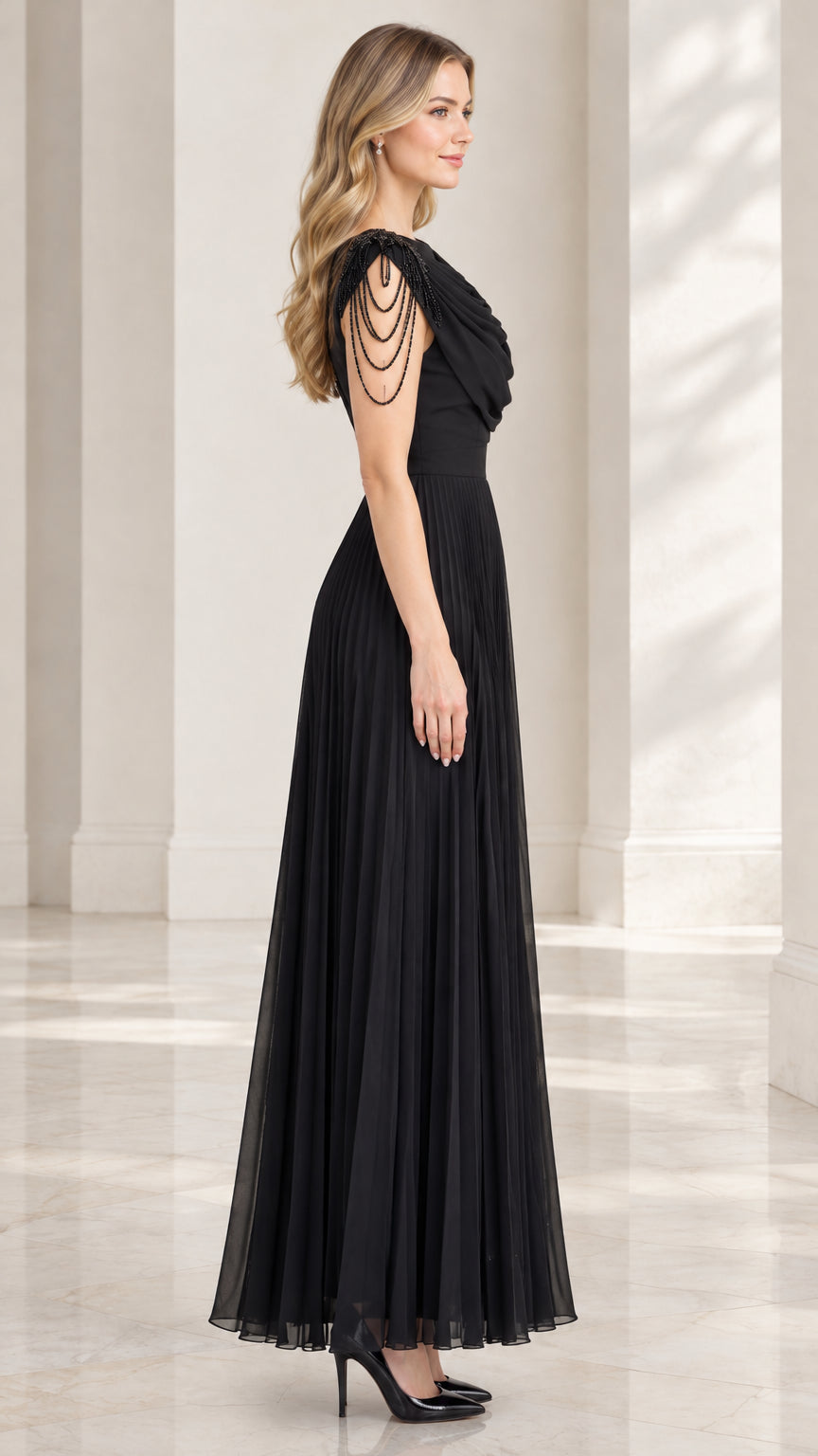 Side profile view of model wearing black draped evening gown with pleated skirt
