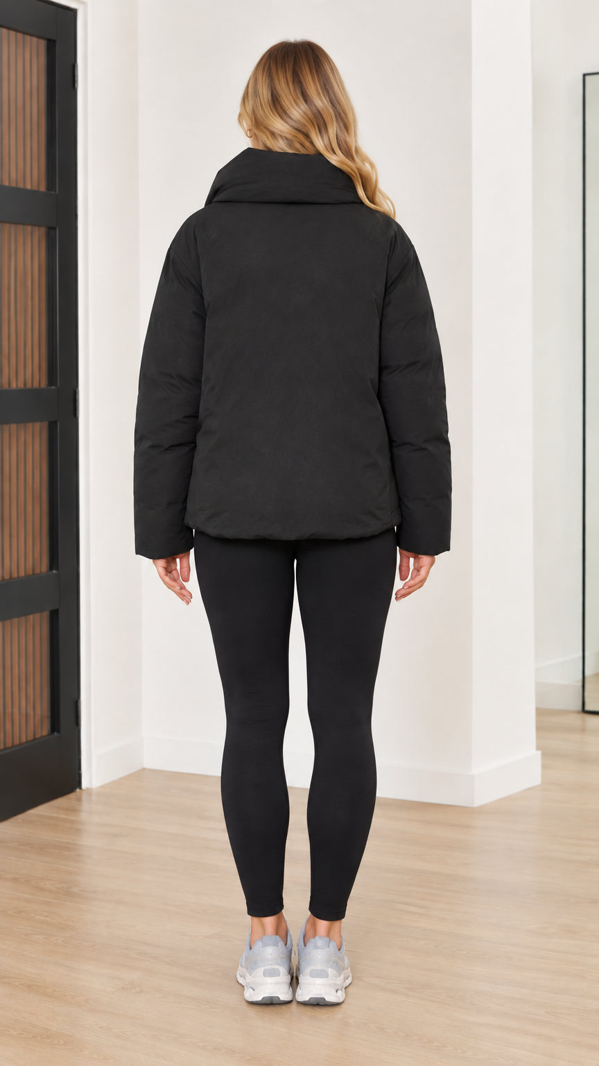 Back view of woman wearing black relaxed fit funnel neck puffer jacket