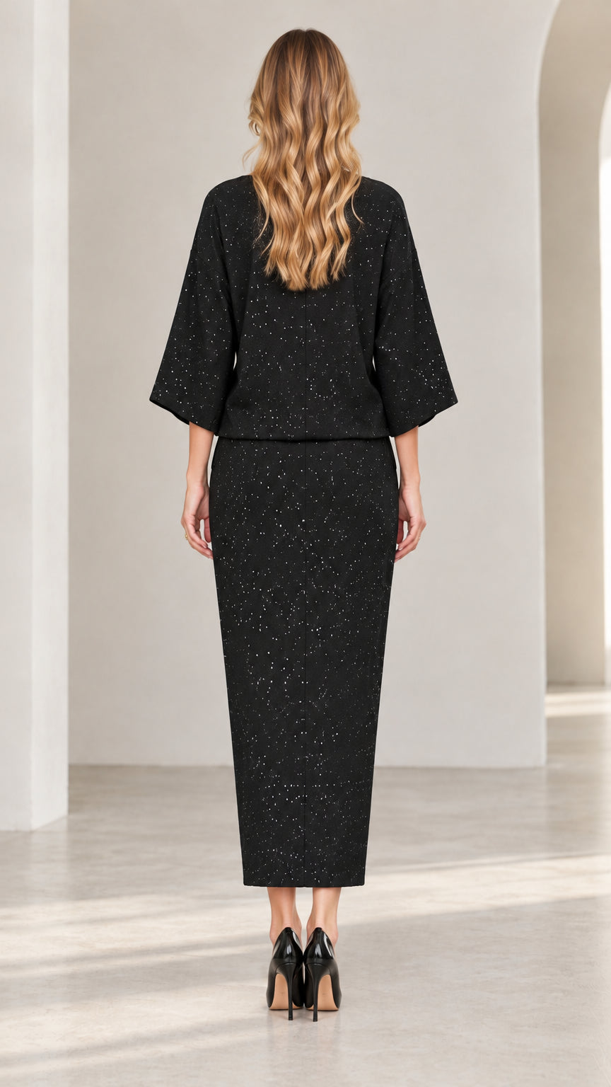 Back view of model wearing black speckled two-piece top and matching pants