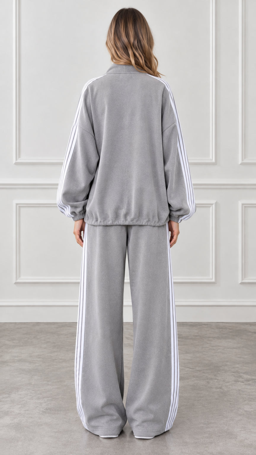 Back view of woman wearing grey zip-up track jacket and wide-leg sweatpants