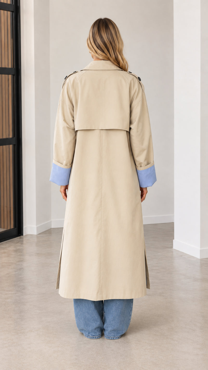 Back view of beige maxi trench coat highlighting the storm flap and long silhouette